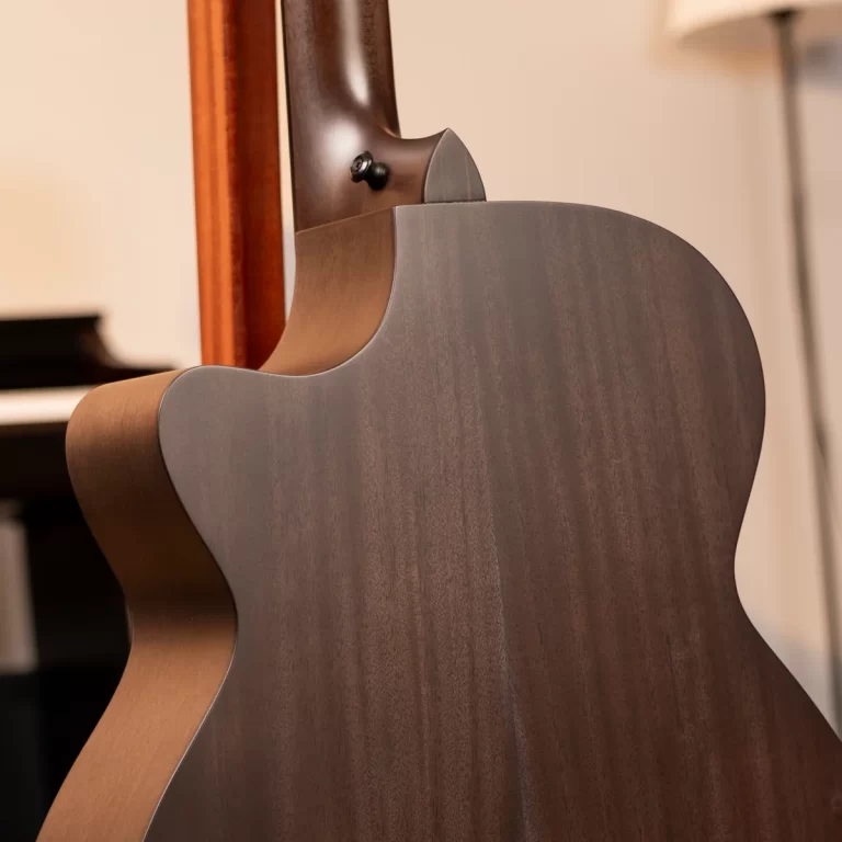 Close-up of the back and cutaway of a wooden acoustic guitar, showing smooth wood grain and the neck joint area. ขายราคาพิเศษ