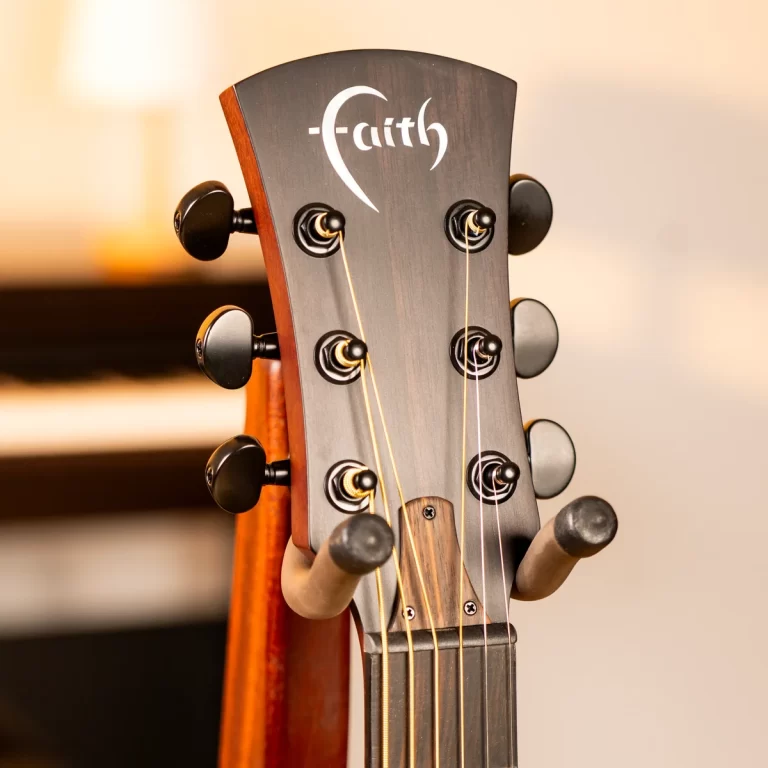 Close-up of a dark wood guitar headstock with six tuning pegs and strings, featuring a white 'Faith' logo at the top. ขายราคาพิเศษ