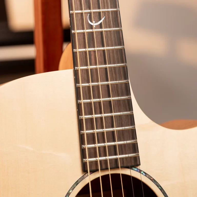 Close-up of an acoustic guitar neck with frets and strings over the body’s soundhole. ขายราคาพิเศษ