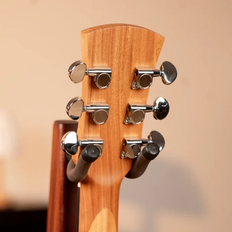 Close-up of a wooden guitar headstock showing six chrome tuning pegs and pegs on the back, highlighting the wood grain color. ขายราคาพิเศษ