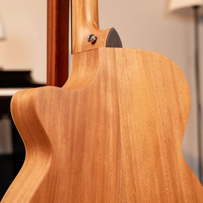 Close-up of a natural wood-bodied acoustic guitar from the back, highlighting the neck joint and smooth curved body edge ขายราคาพิเศษ