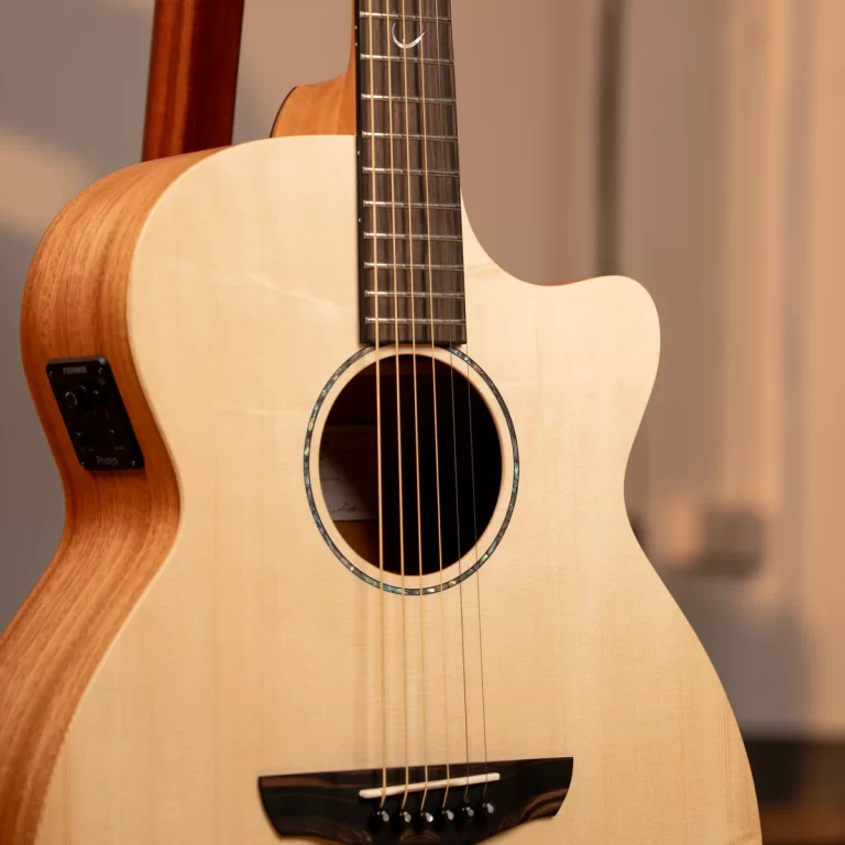 Close-up of an acoustic guitar showing the sound hole, six strings, and light wood top. ขายราคาพิเศษ