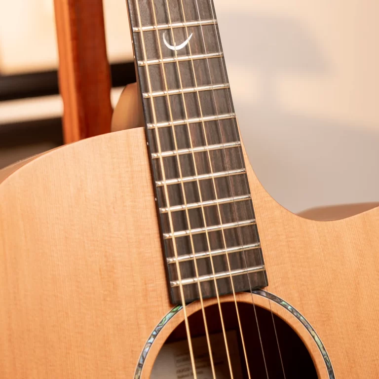 Close-up of an acoustic guitar neck and strings, with frets and wood grain in focus near the soundhole rim. ขายราคาพิเศษ