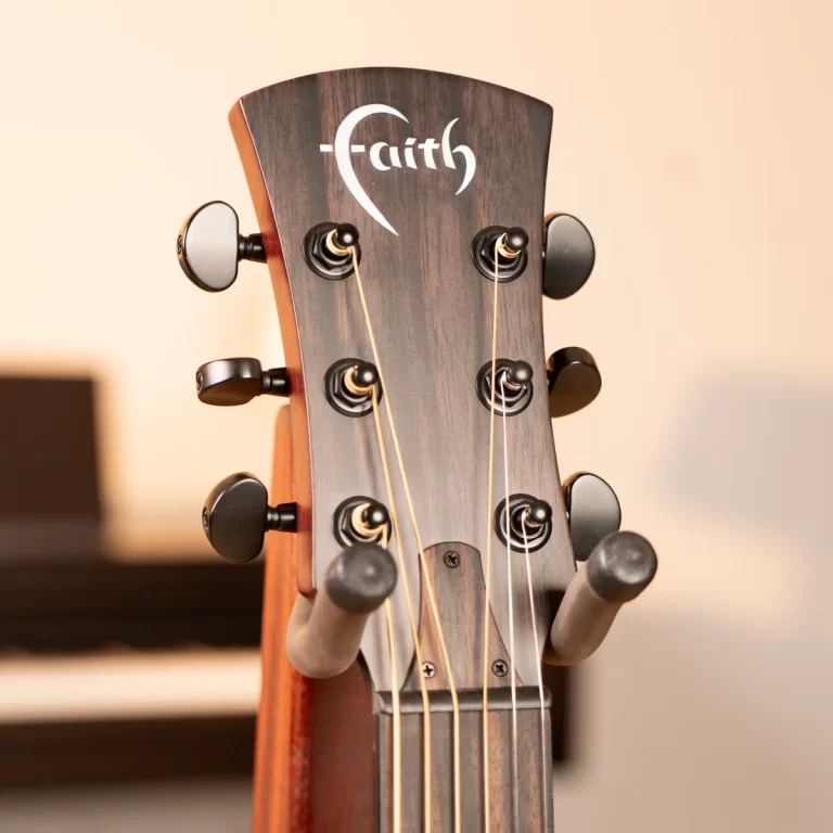 Close-up of a wooden guitar headstock with six tuning pegs and strings, Faith logo visible on the headstock ขายราคาพิเศษ