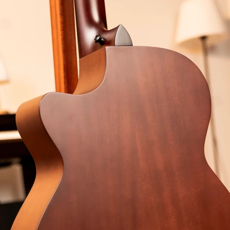 Close-up of the back of a wooden guitar showing a curved cutaway and neck joint. ขายราคาพิเศษ