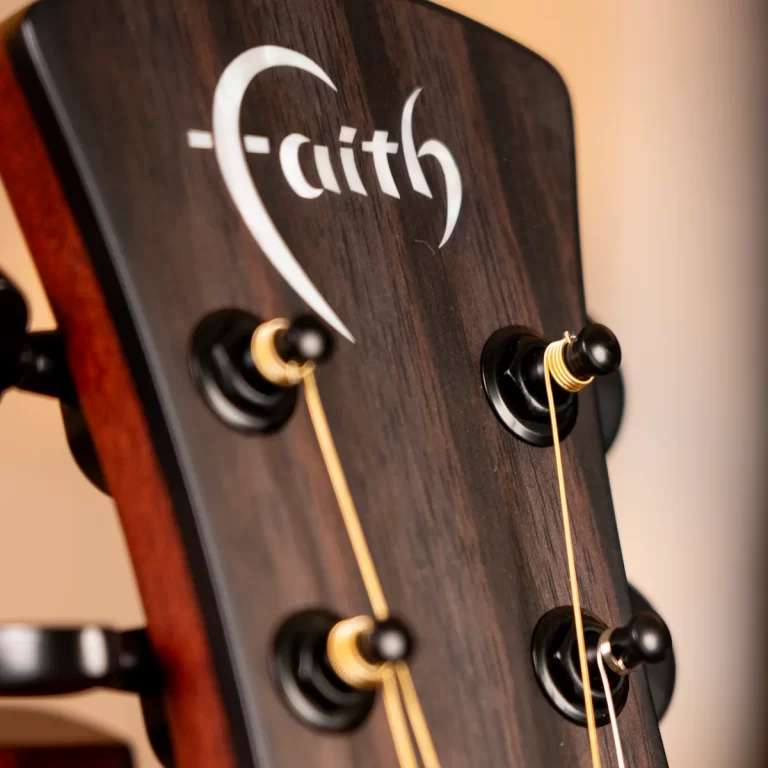 Close-up of a Faith-brand guitar headstock with tuning pegs and strings visible ขายราคาพิเศษ