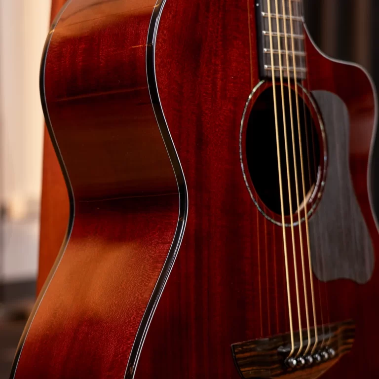 Close-up of a glossy, reddish-brown acoustic guitar showing the body, strings, and soundhole detail ขายราคาพิเศษ