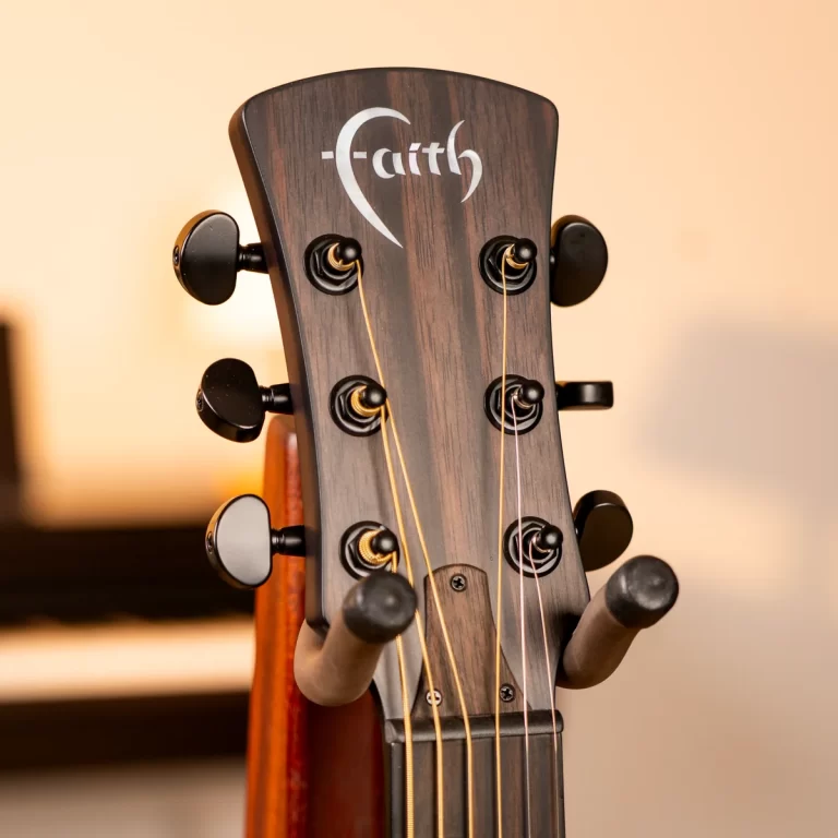 Close-up of a wooden guitar headstock with six tuning pegs and strings, featuring the Faith logo. ขายราคาพิเศษ
