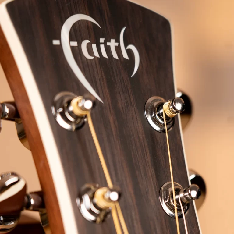 Close-up of a guitar headstock with tuning pegs and strings on dark wood, showing part of the Faith logo ขายราคาพิเศษ