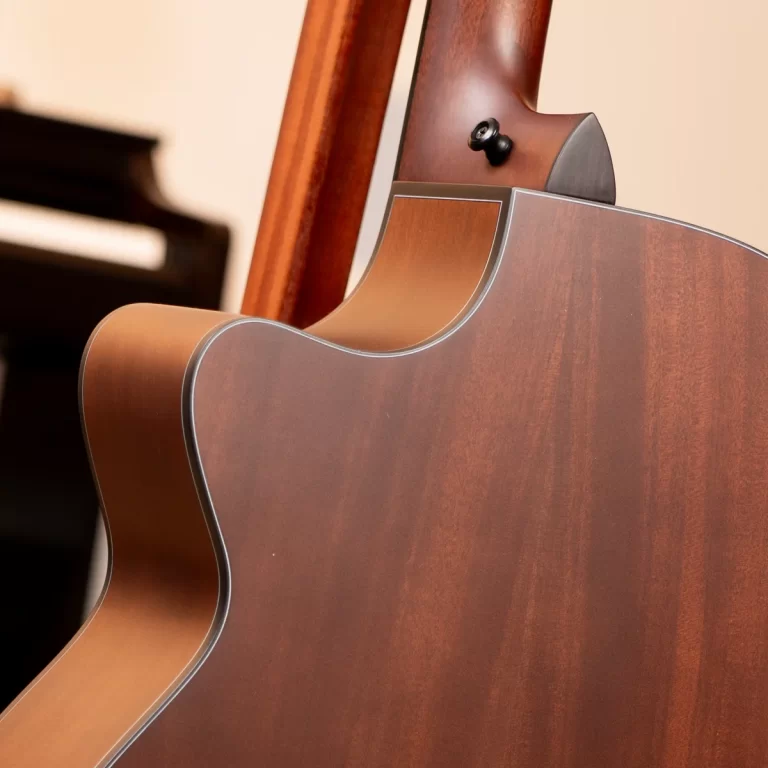 Close-up of a brown acoustic guitar showing a curved cutaway and glossy wood grain finish. ขายราคาพิเศษ