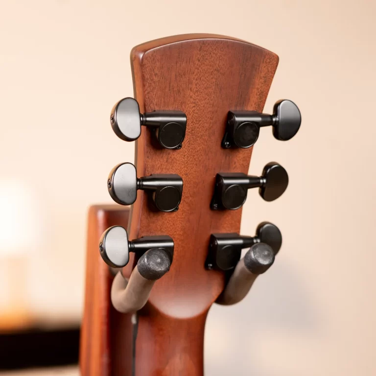 Close-up of a wooden guitar headstock with six black tuning pegs on the side, neutral background ขายราคาพิเศษ