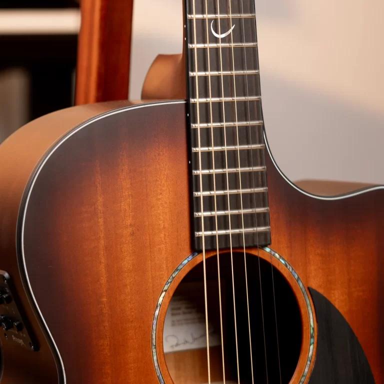 Close-up of a sunburst acoustic guitar, showing the body, fretboard, and six strings in warm light. ขายราคาพิเศษ