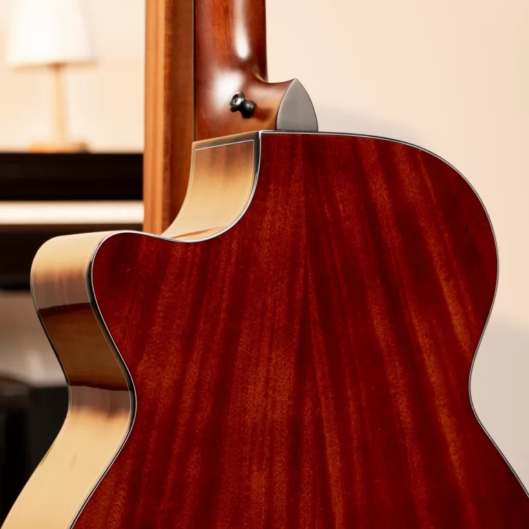Close-up of a glossy reddish-brown acoustic guitar back and side, showing curved body contours and cream binding. ขายราคาพิเศษ