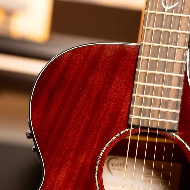 Close-up of a polished red-brown acoustic guitar body with strings and fretboard visible near the soundhole. ขายราคาพิเศษ