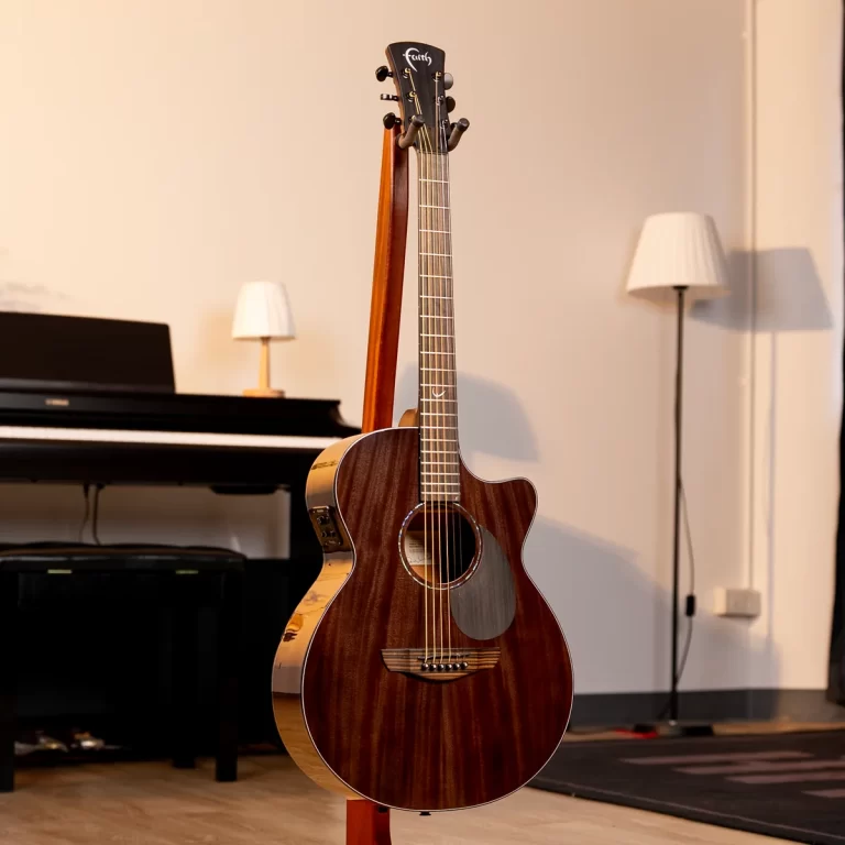 Wooden acoustic guitar on a stand in a warm music-room with a piano in the background ขายราคาพิเศษ