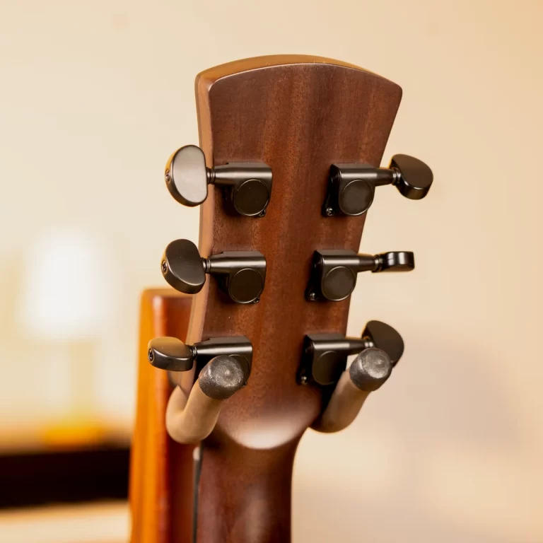 Close-up of a wooden guitar headstock with six black tuning pegs on the sides of the neck. ขายราคาพิเศษ