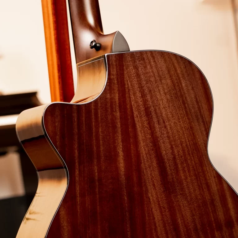 Close-up of a glossy brown acoustic guitar body and neck with curved binding details. ขายราคาพิเศษ