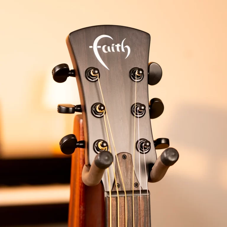 Close-up of a guitar headstock with six tuning pegs and strings, featuring a stylized Faith logo on dark wood ขายราคาพิเศษ