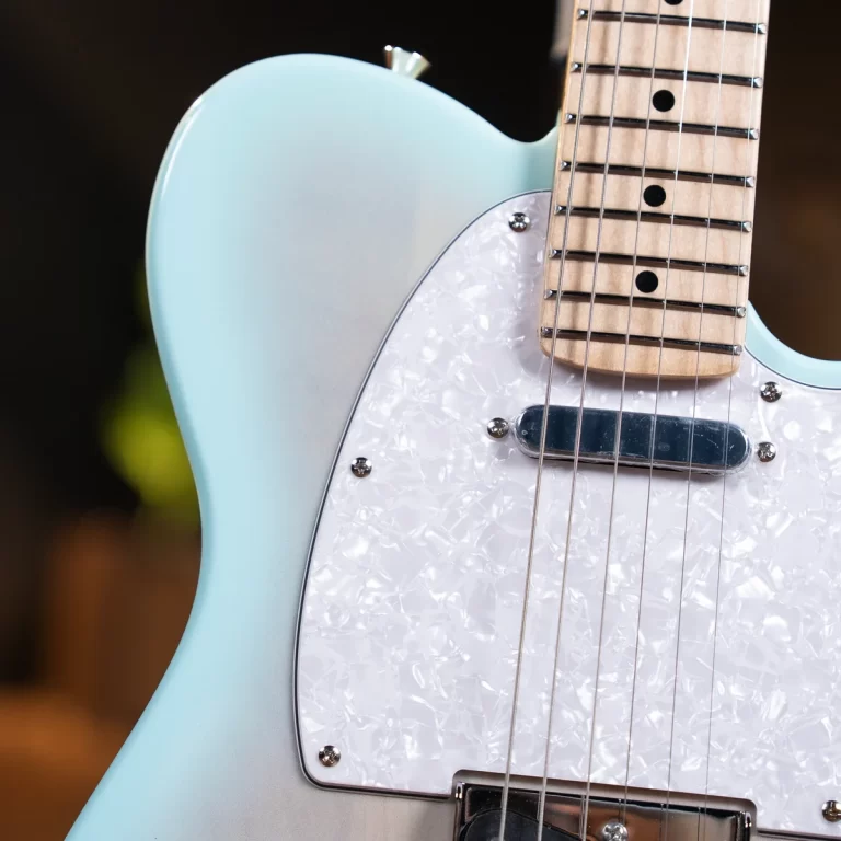 Close-up of a light blue electric guitar with a pearloid pickguard and strings over the pickup, focusing on the body and neck area ขายราคาพิเศษ