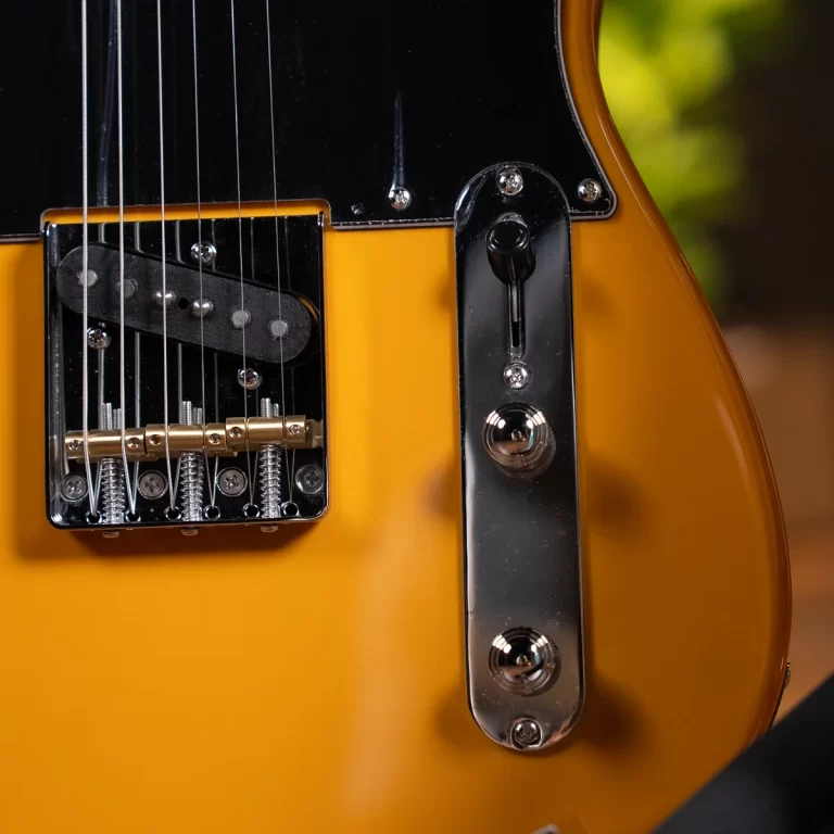 Close-up of a yellow electric guitar showing the bridge, strings, and chrome control plate/bridge hardware. ขายราคาพิเศษ