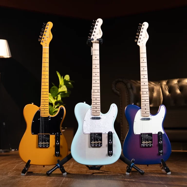Three electric guitars on floor stands in a dim room, from left to right amber, pale blue, and purple bodies. ขายราคาพิเศษ