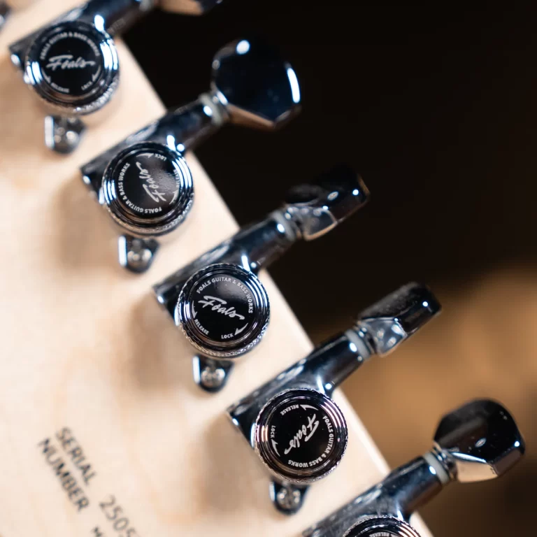 Close-up of chrome guitar tuning pegs on a light wood headstock with Foals branding on the caps. ขายราคาพิเศษ