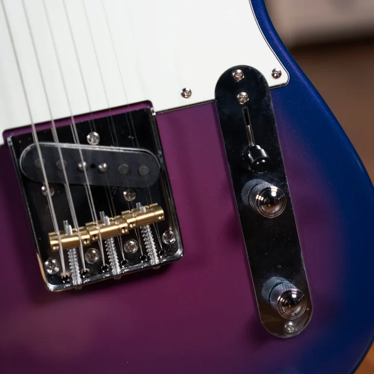 Close-up of a purple electric guitar showing the bridge, strings, and chrome control plate near a white pickguard of the body edges. ขายราคาพิเศษ