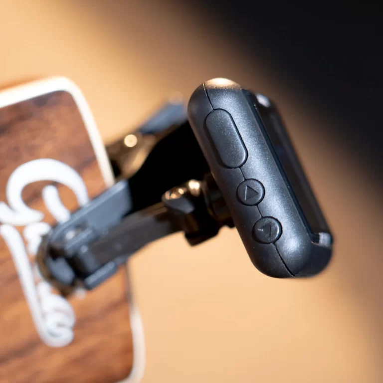 Close-up of a black action camera remote with three round buttons on its side, mounted on a strap. ขายราคาพิเศษ
