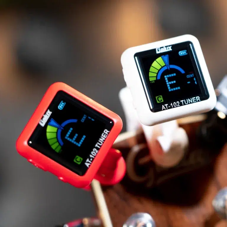 Two clip-on guitar tuners (red and white) attached to a guitar headstock, displaying bright digital screens for tuning. ขายราคาพิเศษ