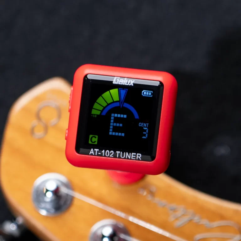 Red AT-102 guitar tuner mounted on a wooden guitar headstock, displaying note E on screen ขายราคาพิเศษ