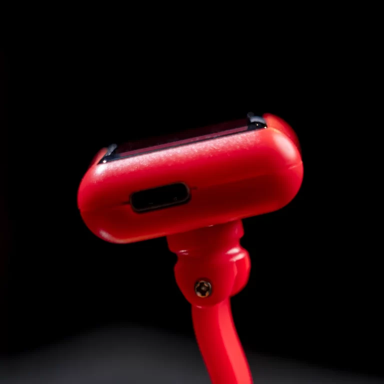 Close-up of a red handheld device with a USB-C-like port on its side against a black background. ขายราคาพิเศษ