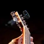 Close-up of a guitar headstock with chrome tuning pegs and a clip-on digital tuner displaying pitch. ขายราคาพิเศษ