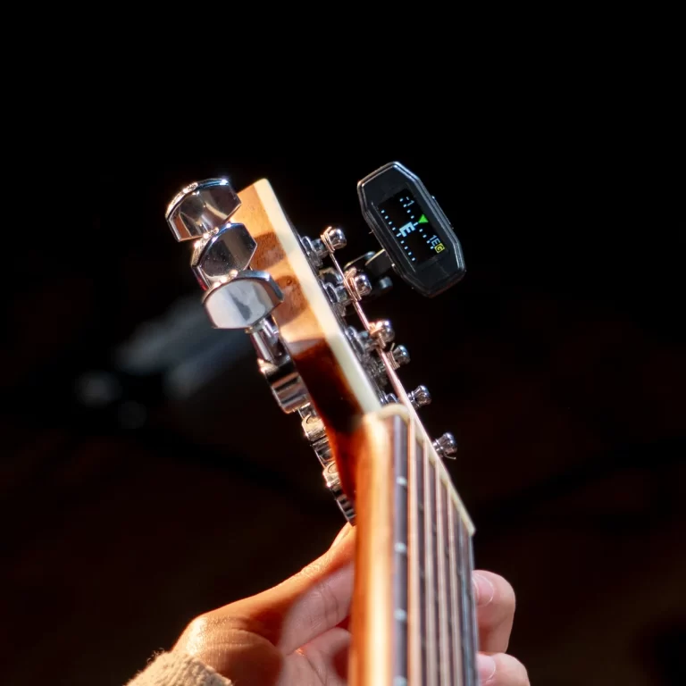 Close-up of a guitar headstock with chrome tuning pegs and a clip-on digital tuner displaying pitch. ขายราคาพิเศษ