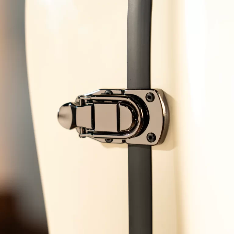 Close-up of a chrome cabinet latch securing a white door with a vertical gray hinge rail ขายราคาพิเศษ