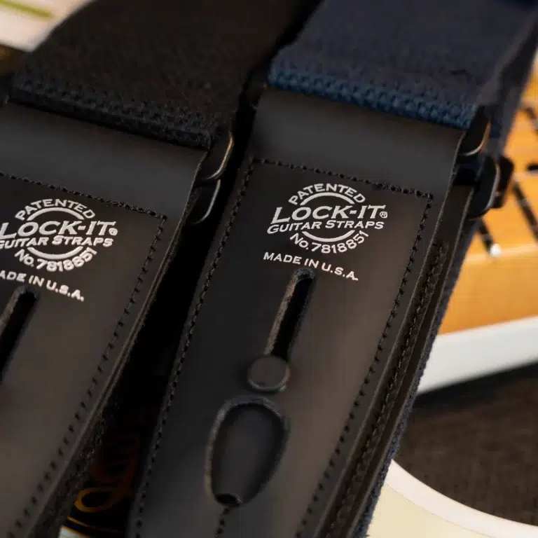 Close-up of a black leather guitar strap with a visible 'LOCK-IT' patent label and 'Made in U.S.A.' text ขายราคาพิเศษ