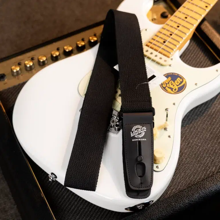 Close-up of a white electric guitar with a black strap and a strap-lock on the body. ขายราคาพิเศษ