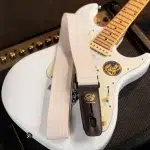 White electric guitar with a light beige strap draped over its body, close-up shot. ขายราคาพิเศษ