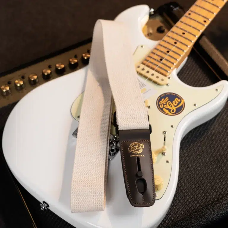 White electric guitar with a light beige strap draped over its body, close-up shot. ขายราคาพิเศษ