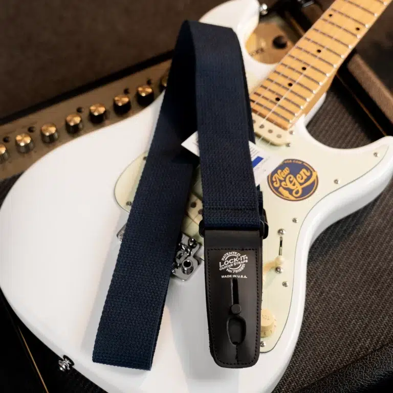 White electric guitar with a dark blue strap draped over its body; a black strap lock labeled 'Lock-It' is visible on the strap end. ขายราคาพิเศษ