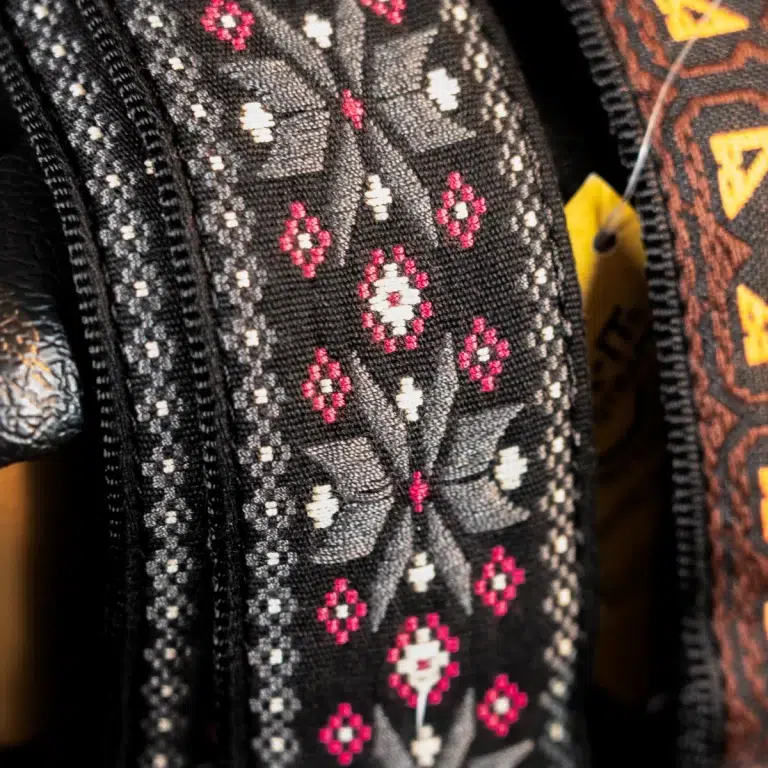 Close-up of black fabric with a geometric white-and-pink diamond pattern. ขายราคาพิเศษ