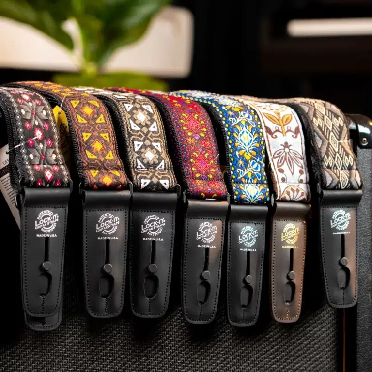Row of colorful patterned guitar straps with black leather ends, hanging on a guitar amp on display. ขายราคาพิเศษ