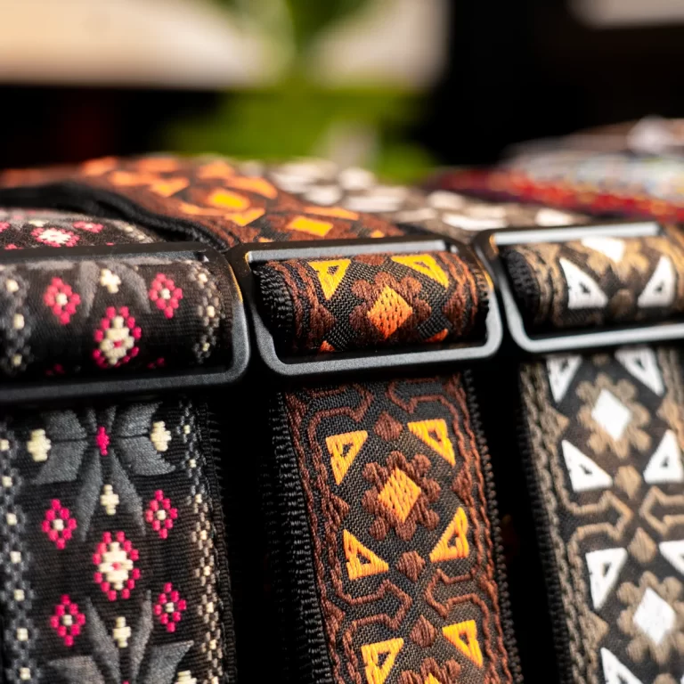Close-up of rolled patterned fabric belts with geometric tribal motifs in black, brown, and orange colors. ขายราคาพิเศษ