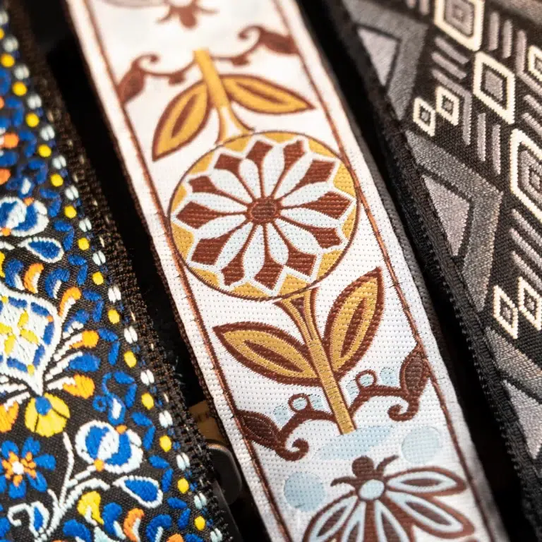 Close-up of decorative fabric trim with a white background and brown-yellow floral pattern. ขายราคาพิเศษ