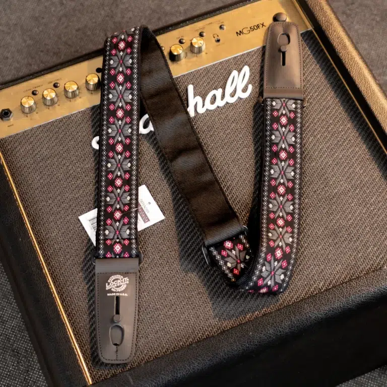 Decorative guitar strap with a pink-and-gray floral pattern draped over a Marshall amplifier. ขายราคาพิเศษ