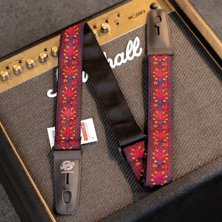 Decorative red-and-gold floral guitar strap with leather ends resting on a Marshall amplifier edge ขายราคาพิเศษ