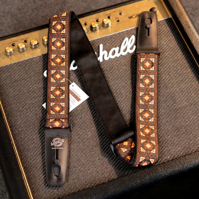 Close-up of a guitar amplifier with a brown geometric-patterned strap laid across it. ขายราคาพิเศษ