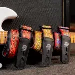 Colorful patterned guitar straps with leather ends draped over an amp, a white electric guitar body visible on the left. ลดราคาพิเศษ