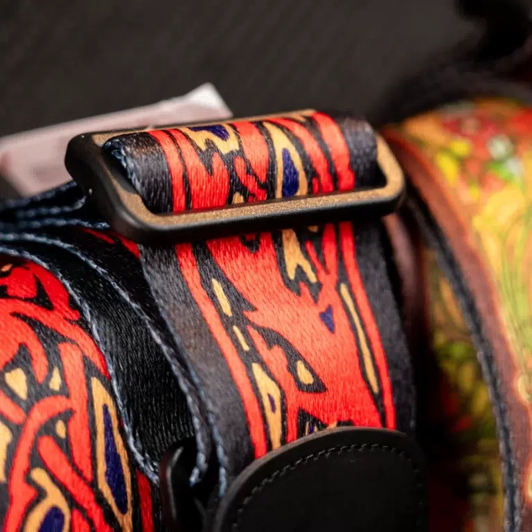 Close-up of a red, blue, and gold patterned fabric strap with a black plastic buckle. ขายราคาพิเศษ