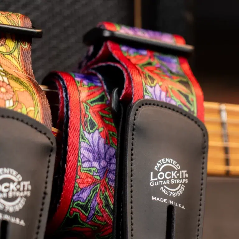 Close-up of colorful floral guitar straps with leather ends and metal hardware, showing Lock-It brand. ขายราคาพิเศษ