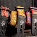 Row of vibrant patterned guitar straps with black leather ends, labeled 'Lock-It Guitar Straps' (Made in USA). ขายราคาพิเศษ